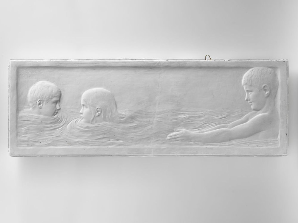 Drei Kinder schwimmen im Wasser mit einer Wand im Hintergrund.