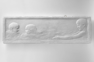 Drei Kinder schwimmen im Wasser mit einer Wand im Hintergrund.