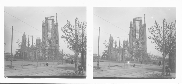 Schwarzes und weißes Foto einer Stadtstraße mit einer Kirche im Hintergrund, die eine Fassadenrestaurierung durchführt, umgeben von Bäumen, Strommasten und Passanten unter einem sichtbaren Himmel.