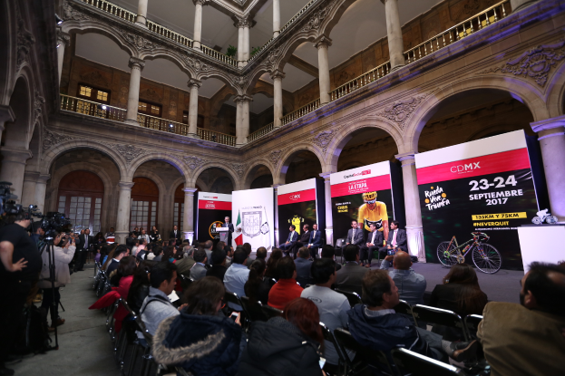 Eine Gruppe von Menschen sitzt an einem Tisch mit einem Podium und einem Mikrofon vor einer Menge, Kameras und Bannern bei einer Pressekonferenz zum CDMX 2017-Event.