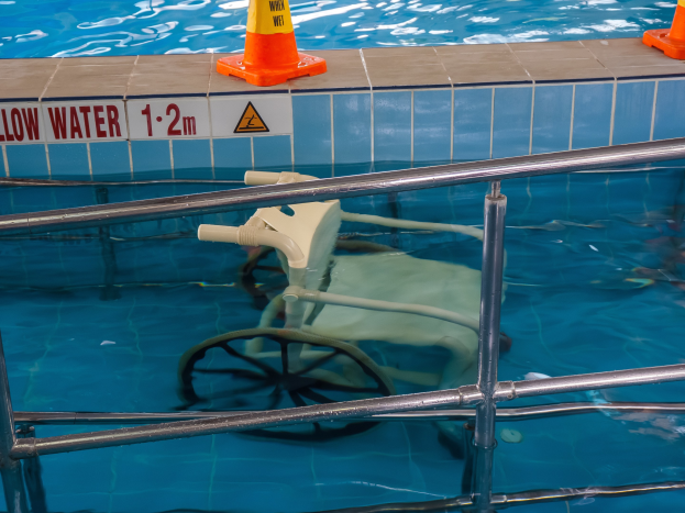 Schwimmbecken mit einem Stuhl in der Mitte, umgeben von Sicherheitskegeln und einem Geländer und einem Schild an der Wand, das die verfügbare Schwimmausrütständigt.