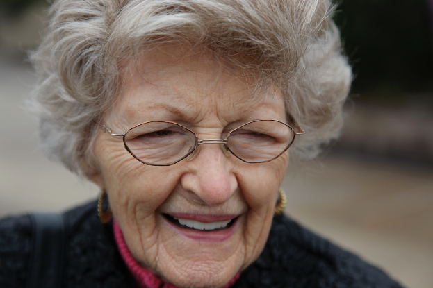 Eine Frau mit Brille lächelt, mit einem unscharfen Hintergrund.