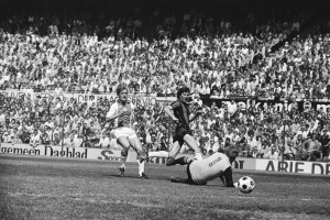 Schwarzes und weißes Foto von Fußballspielern auf einem Feld mit Zuschauern im Hintergrund und einer Tafel mit der Aufschrift "Bundesliga 1978-79 Ajax 1-1 Hannover 96".
