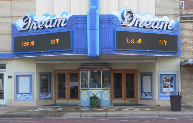 Außenansicht des Dream Theaters in St. Louis, Missouri, mit Glastüren und -fenstern, einem Namensschild, einem Mülleimer, einem Topf mit einer Pflanze und einer Straße unten.