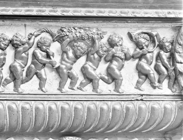 Ein Schwarz-Weiß-Foto einer Gebäude-Seiten-Skulptur, die eine Gruppe von Cherubim zeigt, die verschiedene Musikinstrumente spielen.