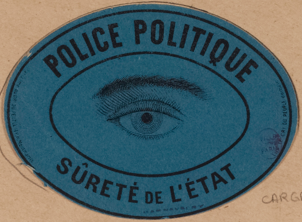 Ein brauner Karton mit einem blauen Aufkleber, der "Polizei Politique Surete de L'Etat" und ein Auge in der Mitte carries.