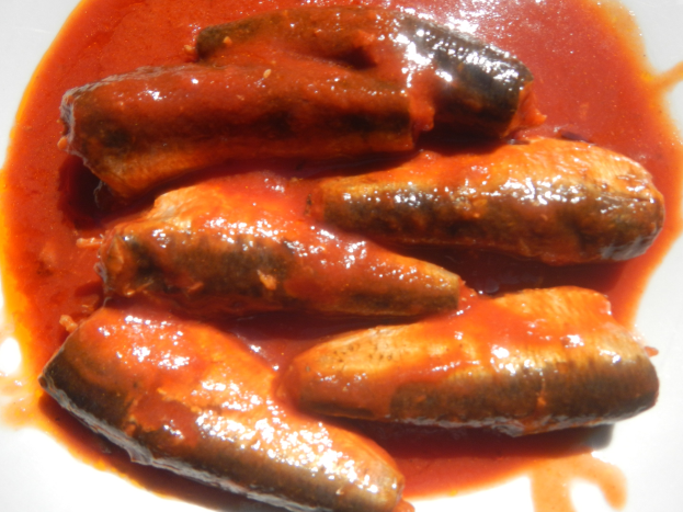 Weißer Teller mit Wurst in roter Sauce.