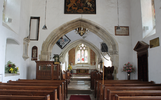 Ein Innenblick in eine Kirche mit Blumenvasen, Bänken, Foto Rahmen und Lichtern.