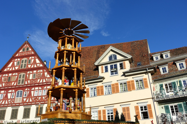 Ein festlicher Weihnachtsmarkt in Rothenburg ob der Tauber, Deutschland, mit einem hölzernen Aufbau in der Mitte, der von Menschen, Pflanzen und anderen Gegenständen umgeben ist, mit dem Himmel im Hintergrund.