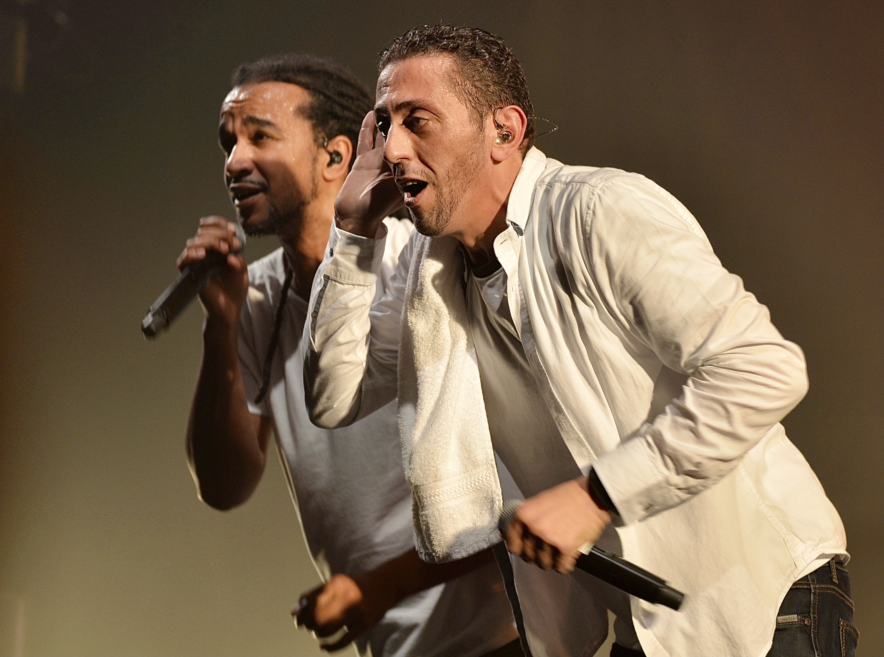 Zwei Männer in legerer Kleidung performen auf der Bühne, jeder hält ein Mikrofon.