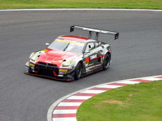 Ein Nissan GT-R Nismo GT3 Rennwagen auf der Nürburgring 24 Stunden Rennstrecke, mit grünem Gras auf beiden Seiten.