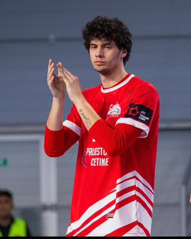 Ein Mann in einem roten und weißen T-Shirt klatscht in der Vordergrund mit einer anderen Person und einer Wand im Hintergrund, mit dem Text "Copenhagen Futsal Club - Foto 1" unten.