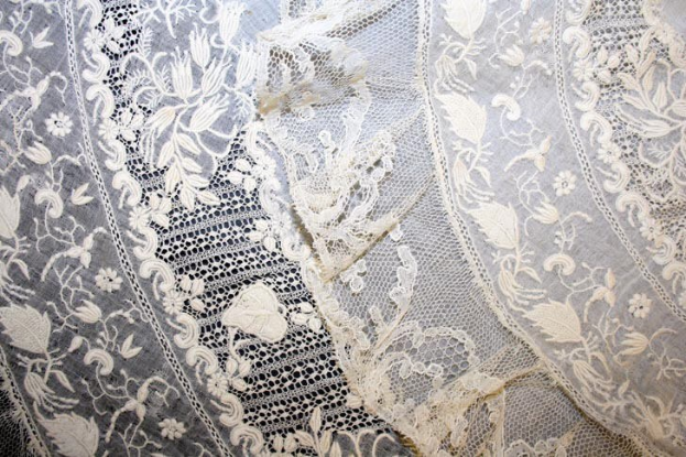 Nahaufnahme eines weißen Hochzeitskleids mit feiner Spitzenverzierung, das zarte Muster und einen leichten, luftigen Stoff aufweist.