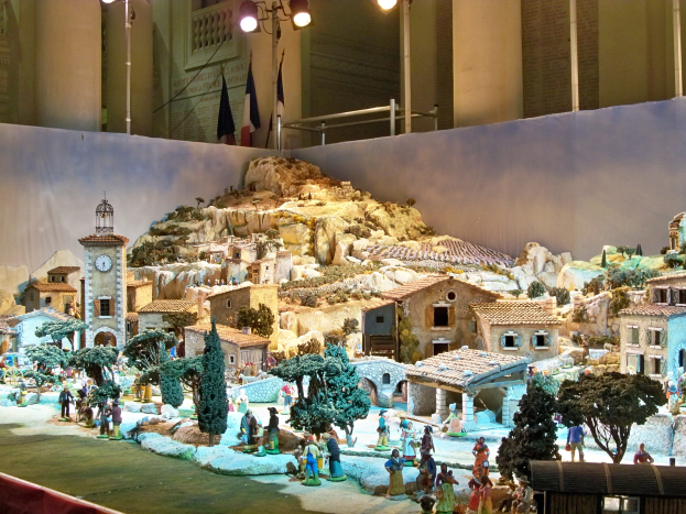 Ein detailliertes Krippenmodell im Museum ausgestellt, mit Figuren, Strukturen und beleuchteten Elementen, die eine festliche Atmosphäre schaffen.