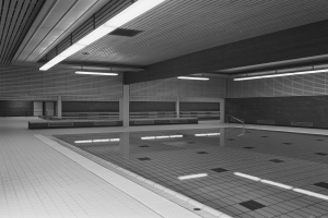 Indoor-Schwimmbad mit klarem Wasser, gefliesten Wänden und Boden, Deckenbeleuchtung und minimalen Umgebungsobjekten in einem großen, ruhigen Raum.