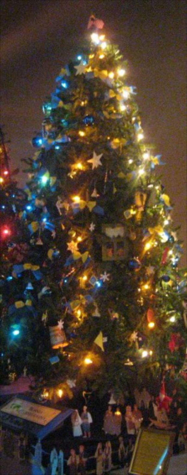 Ein geschm├╝ckter Weihnachtsbaum mit Menschenfiguren auf einem Tisch darunter.