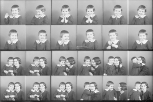 Schwarzes und weißes Foto einer Gruppe von Kindern mit einer Frau in der Mitte, die ein Baby hält und beide warmherzige Ausdrücke zeigen.