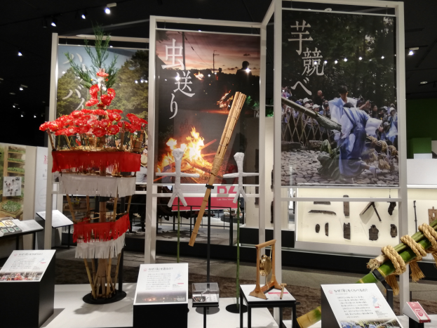 Ein Raum voller verschiedener Gegenstände, darunter Schilder mit Text, Stände und andere Objekte, mit Schildern mit Bildern und Text sowie Deckenlampen, die eine festliche Atmosphäre bei der Tokyo Toy Fair 2019 schaffen.