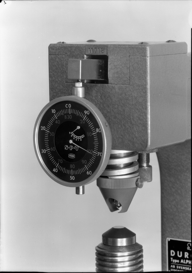 Ein Schwarz-Weiß-Foto eines Messgeräts, einer Maschine zur Messung der Dicke eines Metallstücks.