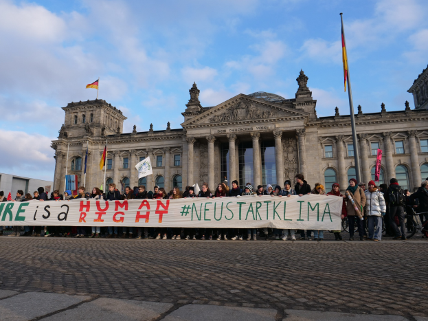 Gruppe von Menschen vor dem Reichstaggebäude in Berlin mit einem Banner mit der Aufschrift "Wir sind ein Menschenrecht."