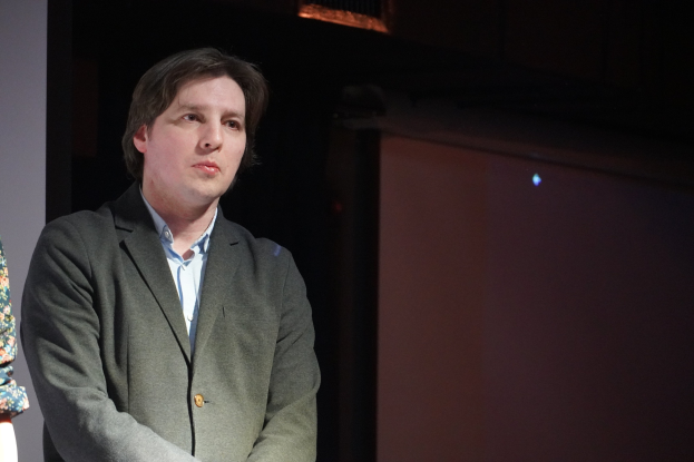 Zwei Menschen in Abendgarderobe stehen nebeneinander auf einer Bühne mit ernsten Gesichtern.