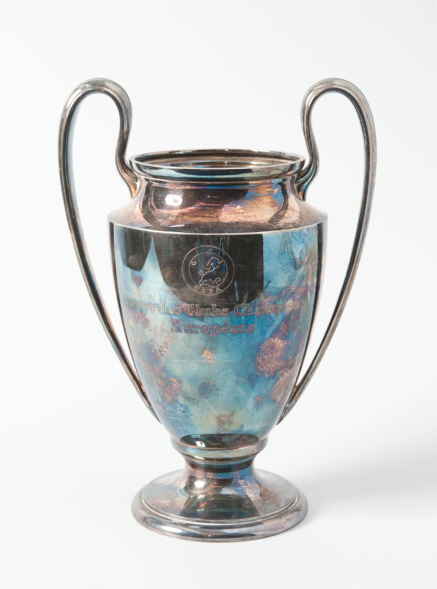 Der UEFA-Champions-League-Pokal, ein stahlerner Becher mit zwei Griffen und einem blauen und silbernen Farbschema, beschriftet mit «UEFA Champions League», gegen einen weißen Hintergrund dargestellt.