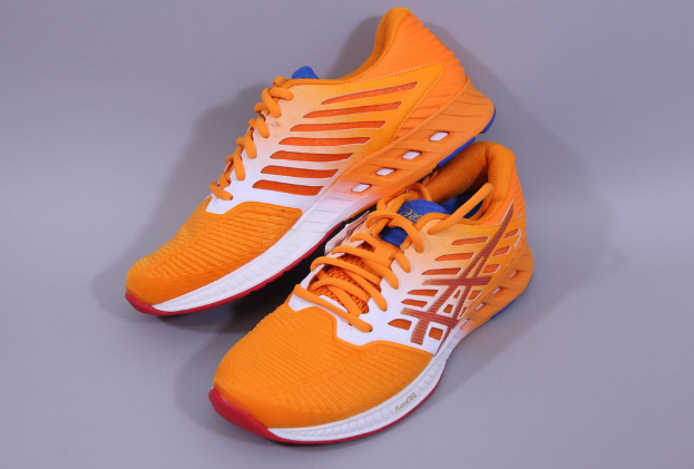 Ein Paar Asics Gel-Nimbus 22 Laufschuhe in Orange, Weiß und Blau auf einer grauen Oberfläche, mit einem Mesh-Obermaterial, einer gepolsterten Zwischensohle und einer strapazierfähigen Außensohle.
