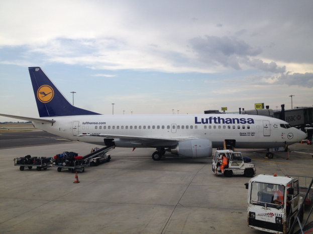 Lufthansa Airbus A320-200 auf dem Frankfurter Flughafen geparkt mit Bodenfahrzeugen, Verkehrskegeln und Beschilderung bei bewölktem Wetter.