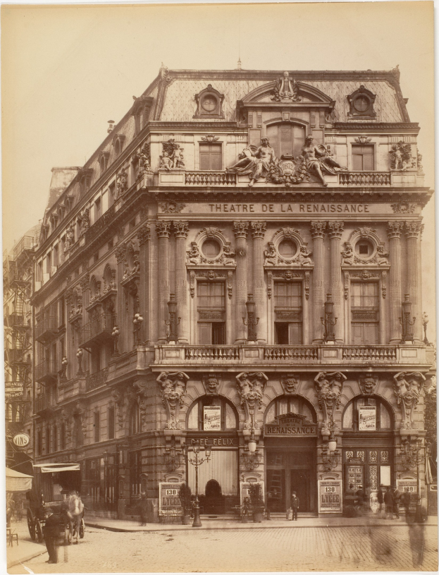 Schwarz-weiß-Foto des Théâtre de la Renaissance in Paris mit einer Fassade mit Fenstern, Säulen, Bögen und Skulpturen sowie einigen Menschen und Fahrzeugen auf der Straße davor und dem Himmel im Hintergrund.