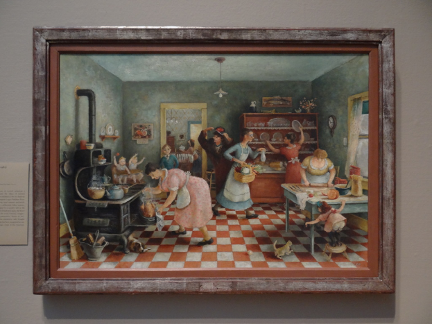 Ein Fotoраhmen an der Wand zeigt ein Bild von mehreren Frauen in einem Raum, die verschiedene Tätigkeiten ausführen.