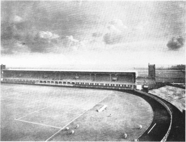 Schwarzes und weißes Foto eines Fußballfeldes mit einem Stadion im Hintergrund, umgeben von Bäumen, Wolken am Himmel und Text 'Stoke City Football Club' unten.