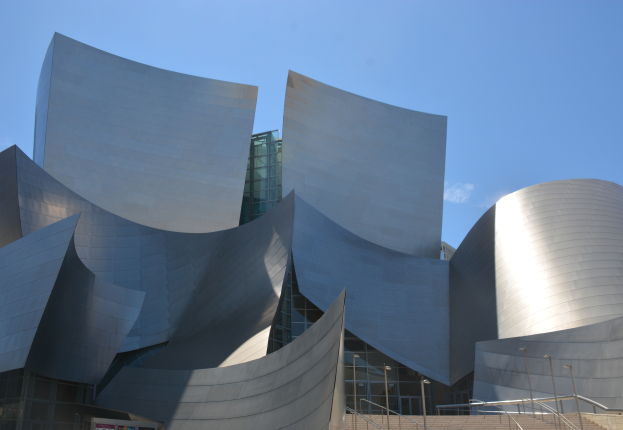 Das ARTIST Concert Hall in Los Angeles, ein modernes Geb"ude mit Glaswänden und Treppen mit Geländern, die zum Eingang führen, umgeben von Laternenmasten, mit einer Tafel mit Text im Vordergrund und einem bewölkten Himmel im Hintergrund.